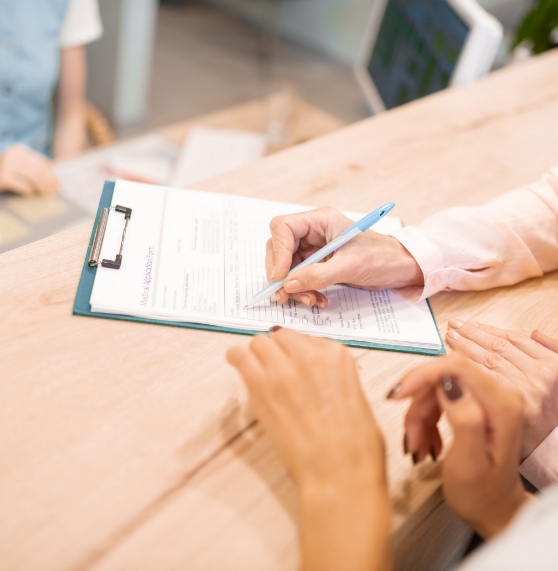 Dental team member showing a patient where to sign on a clipboard