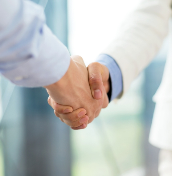 Two medical professionals in white lab coats shaking hands