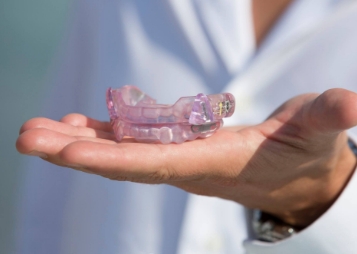 Sleep apnea dentist holding a light purple oral appliance