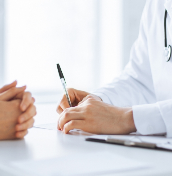 Sleep dentist holding a pen while sitting across table from a patient