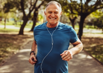 Man in blue tee shirt smiling while jogging