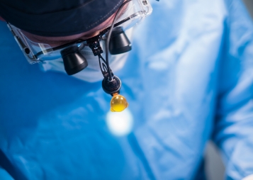 Doctor wearing medical binoculars while performing surgery