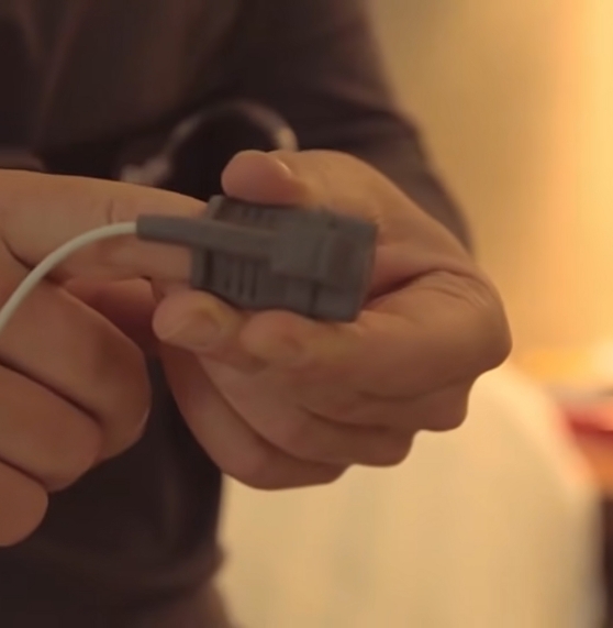 Person putting a pulse oximeter on their finger