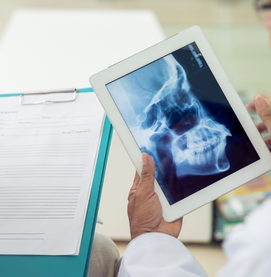 Two dentists looking at an x ray of a patients jaws and teeth