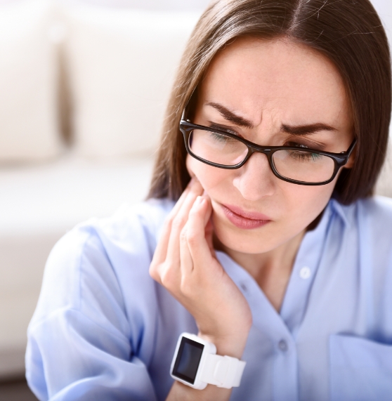 Woman wincing while holding her jaw in pain