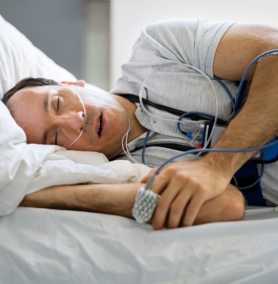 Man sleeping on his side while hooked up to various sleep study monitors