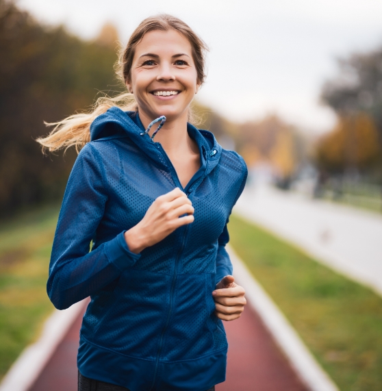 Woman in blue jacket smiling while jogging